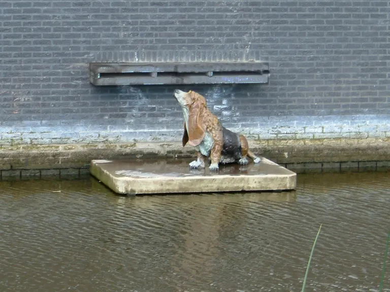 Bronzen Basset Hound onder water spuwer (vanaf de overkant)